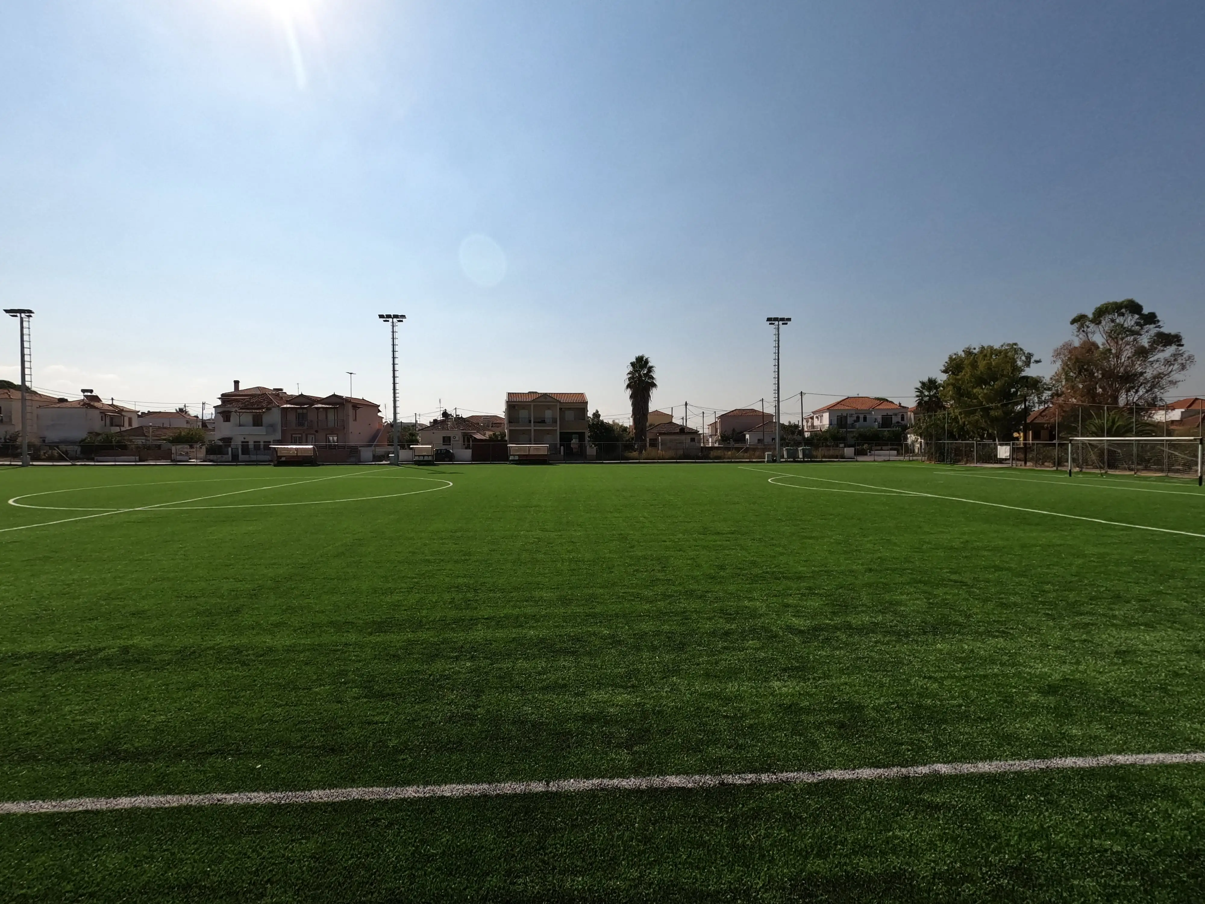 Γήπεδο Καλλονής όπου απεικονίζεται ο τεχνιτός χλωροτάπητας, ένα από τα δύο καινούργια τέρματα, η σέντρα και στο βάθος φαίνονται οι τρείς καινούργιοι ιστοί φωτισμού του γηπέδου.